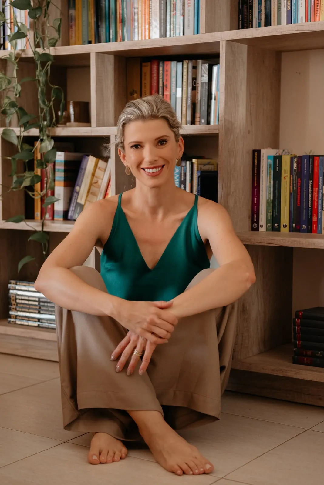 Caroline Kirsten Reis sentada em frente a uma estante de livros
